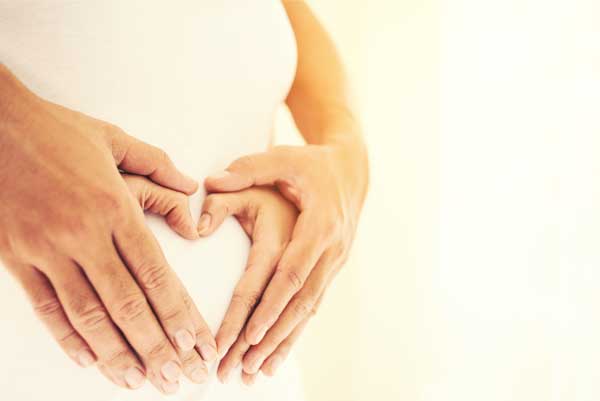 schwangere Frau und Hände auf dem Bauch